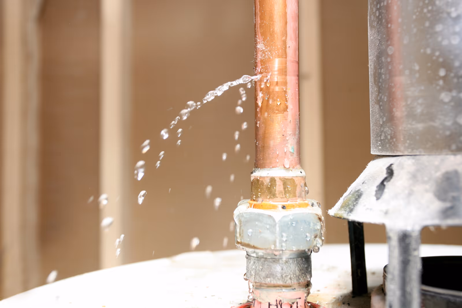 A bust pipe is gusing water, creating a large leak in a room. Water sprays forcefully from a crack in the pipe, pooling on the floor. This can potentially lead to water damage.