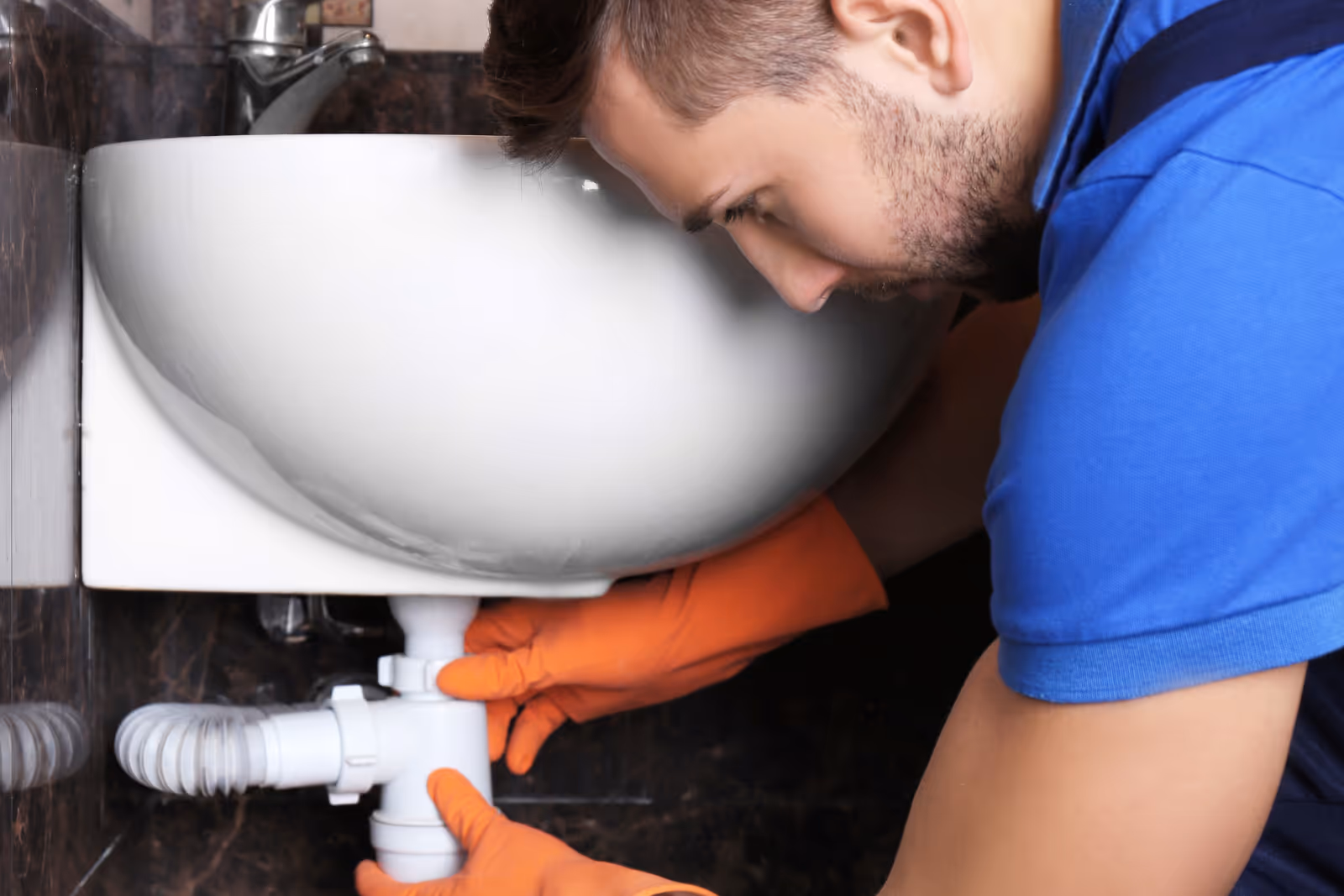Plumber repairing a clogged drain in a residential kitchen.